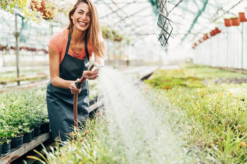 Woman watering plants in large garden centre